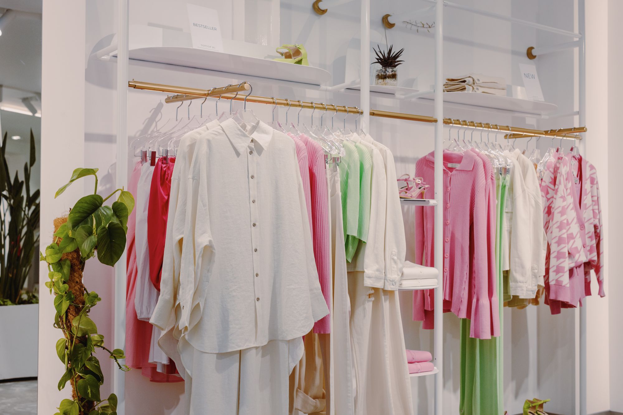 White, pink, and green clothes on a brass rail