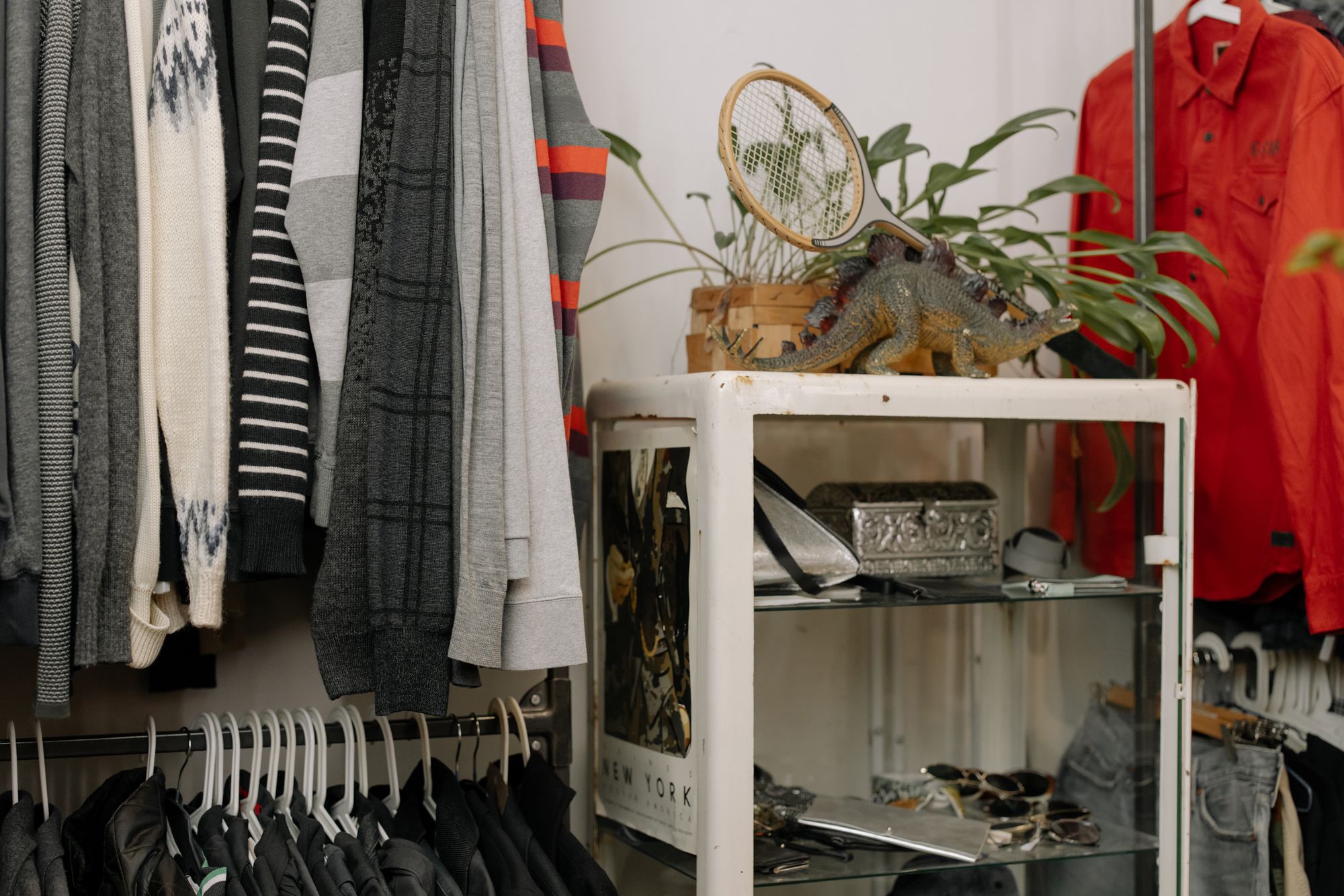 Knitwear and shirts hanging beside a shelf of small accessories