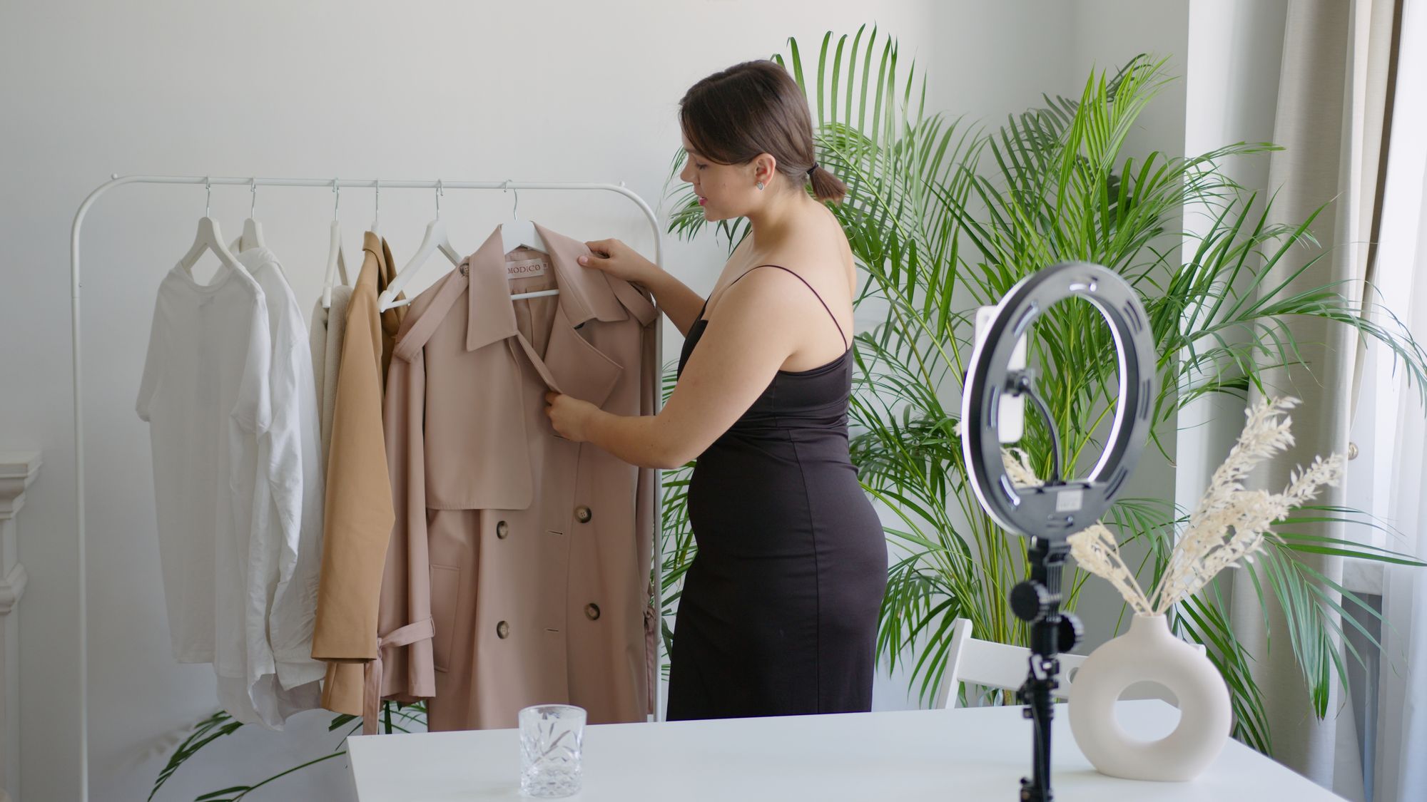 A coat arranged on a rail in front of a ring light